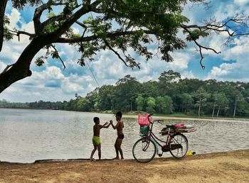 Bicycles on bicycle by lake against sky