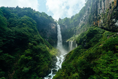 Scenic view of waterfall in forest against sky