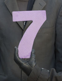 Close-up of hand holding pink against wall