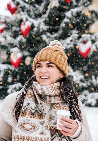 Portrait of a young woman drinking coffee from a paper coffee to go cup. winter, christmas, snowing.