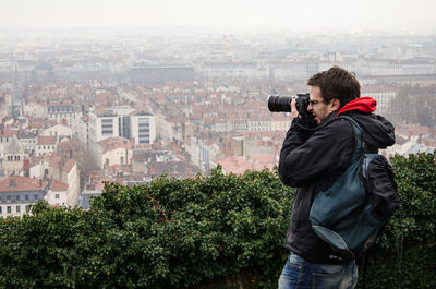 Side view of man photographing cityscape through camera