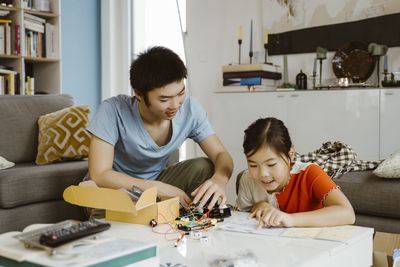 Siblings helping each other while assembling science project at home