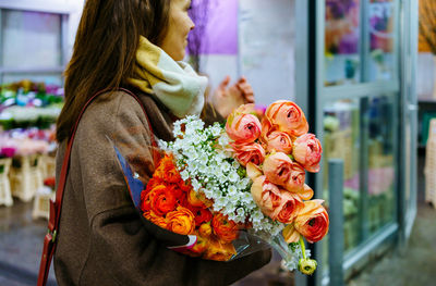 Woman with large bouquet of peonies flowers at flower market