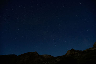 Low angle view of silhouette mountain against sky at night full of stars