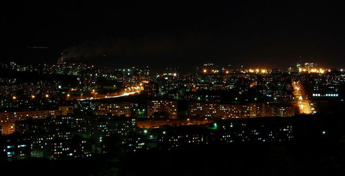 Illuminated cityscape against sky at night