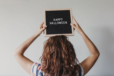Woman holding happy halloween text against white background