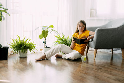 Young woman using digital tablet while sitting on sofa at home