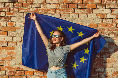 Young woman standing against brick wall