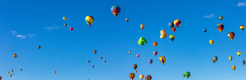 Low angle view of hot air balloons against clear blue sky