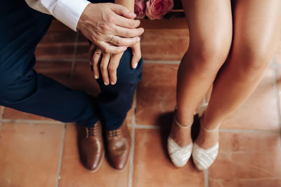 Low section of couple holding hands sitting on bench