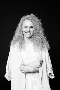 Portrait of a smiling young woman against black background