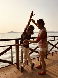 Full length of women standing on pier over sea against sky