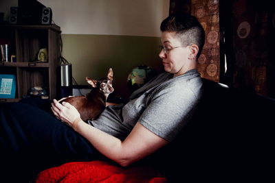 Woman sitting on sofa with dog at home