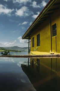 House on lake by building against sky