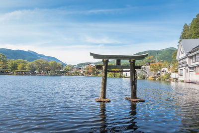 Wooden posts in lake against sky