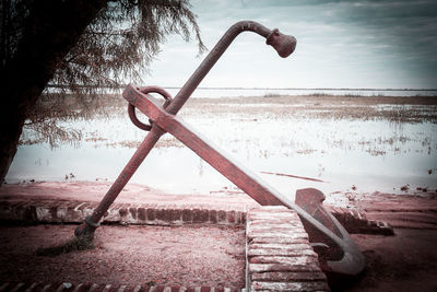 Close-up of metal structure on beach against sky