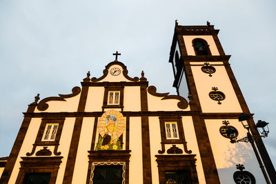 Low angle view of cross on building against sky