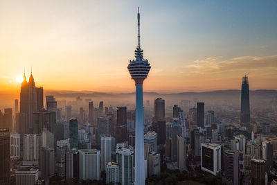 Modern buildings in city against sky during sunset