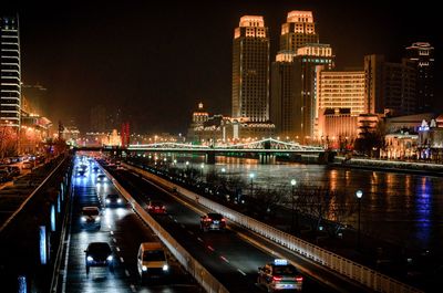 Illuminated bridge amidst buildings in city at night