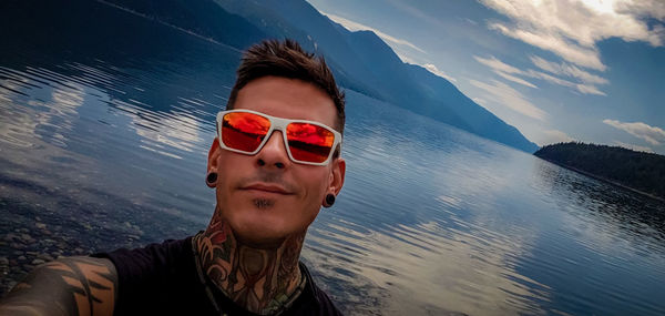 Portrait of young man wearing sunglasses against sky