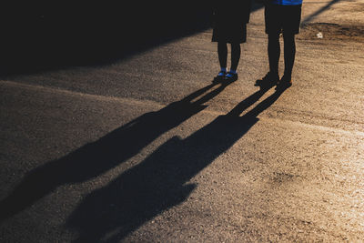 Low section of people standing on street during sunset