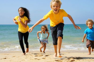 Full length of happy friends enjoying at beach