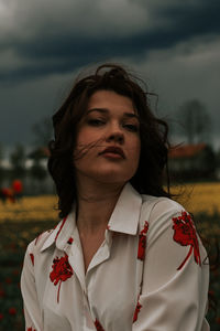 Portrait of young woman standing against sky