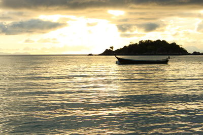 Boats in calm sea against cloudy sky
