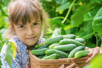 Portrait of girl with cucumbers in basket
