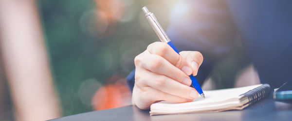 Business woman hand writing on a notepad with a pen in the office. for web banner.soft focus