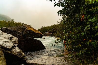 Scenic view of rocks by river against sky