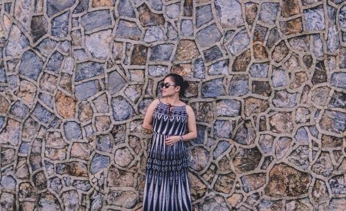 Full length portrait of woman standing against wall