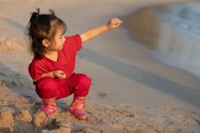 Full length of cute girl crouching at beach