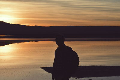 Silhouette man standing on beach against sky during sunset