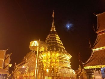 Low angle view of illuminated buildings against sky at night