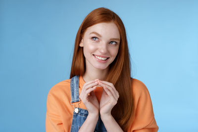 Young woman day dreaming against blue background