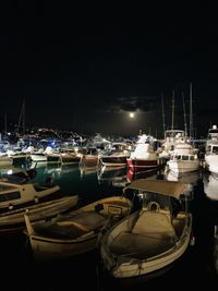 Boats moored in harbor at night