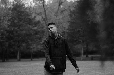 Portrait of young man standing against trees