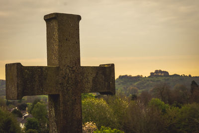 Cross on grass against sky