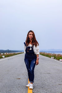 Portrait of smiling young woman standing on road