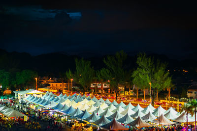 Chairs and tables in illuminated city against sky at night