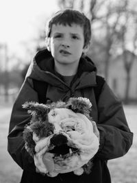 Boy making face while holding dog mask at park