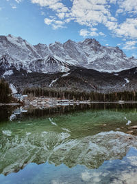 Scenic view of lake by snowcapped mountains against sky