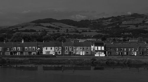 Houses by lake against sky in city