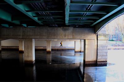 Distant view of person walking on footpath by charles river below bridge