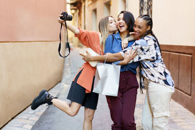 Cheerful female friends embracing in alley