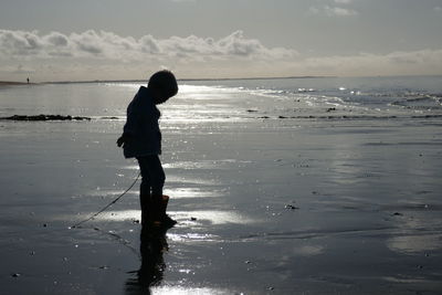 Side view of silhouette boy standing on beach