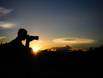 Silhouette man standing on field against sky during sunset