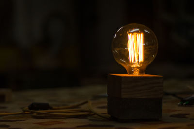 Close-up of illuminated light bulb on table