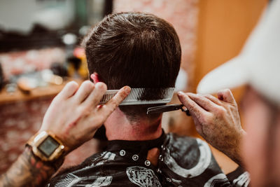 Cropped hands of barber grooming customer in salon